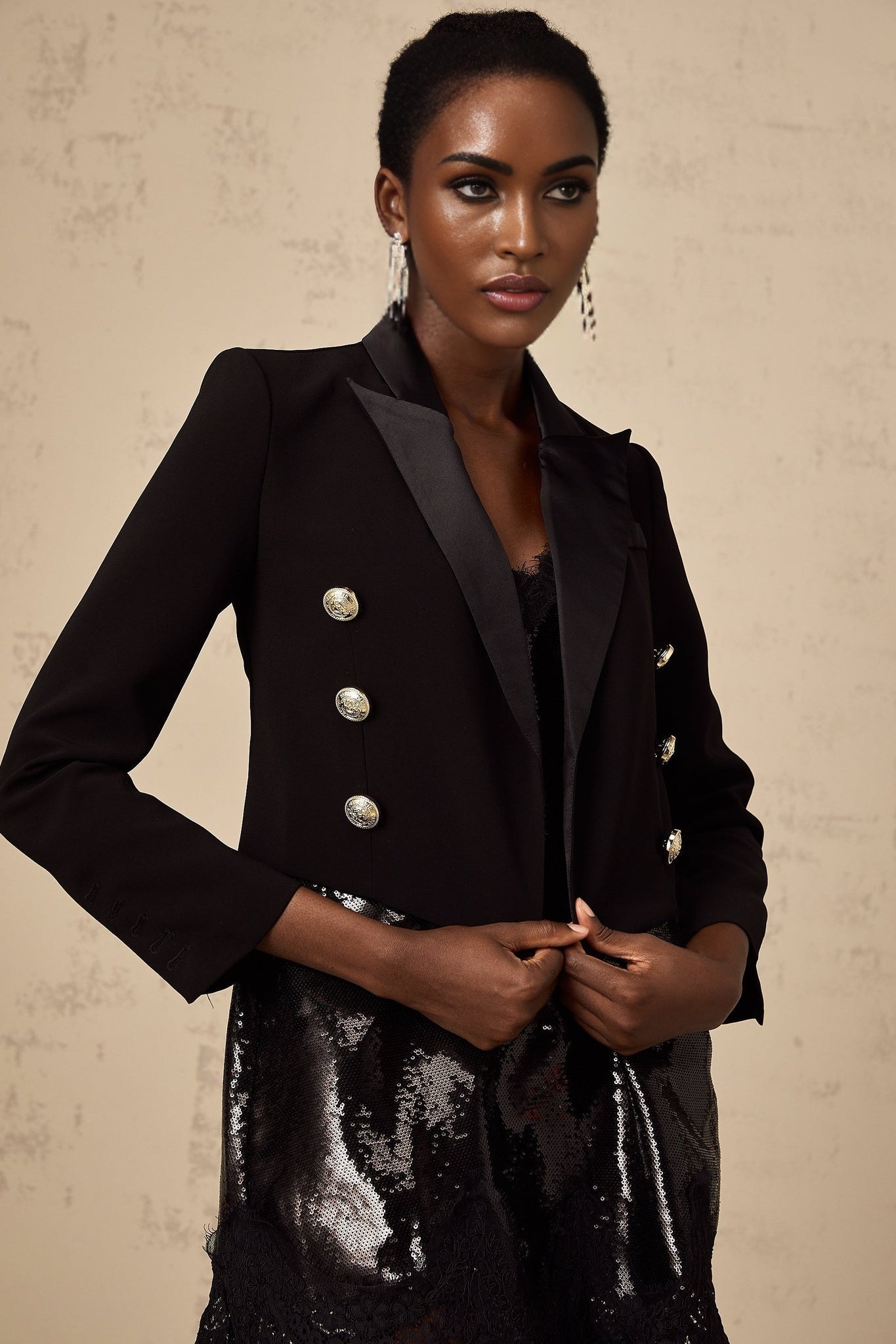 A black cropped blazer with doublebreasted front closure named Giulia worn by a model against a plain background