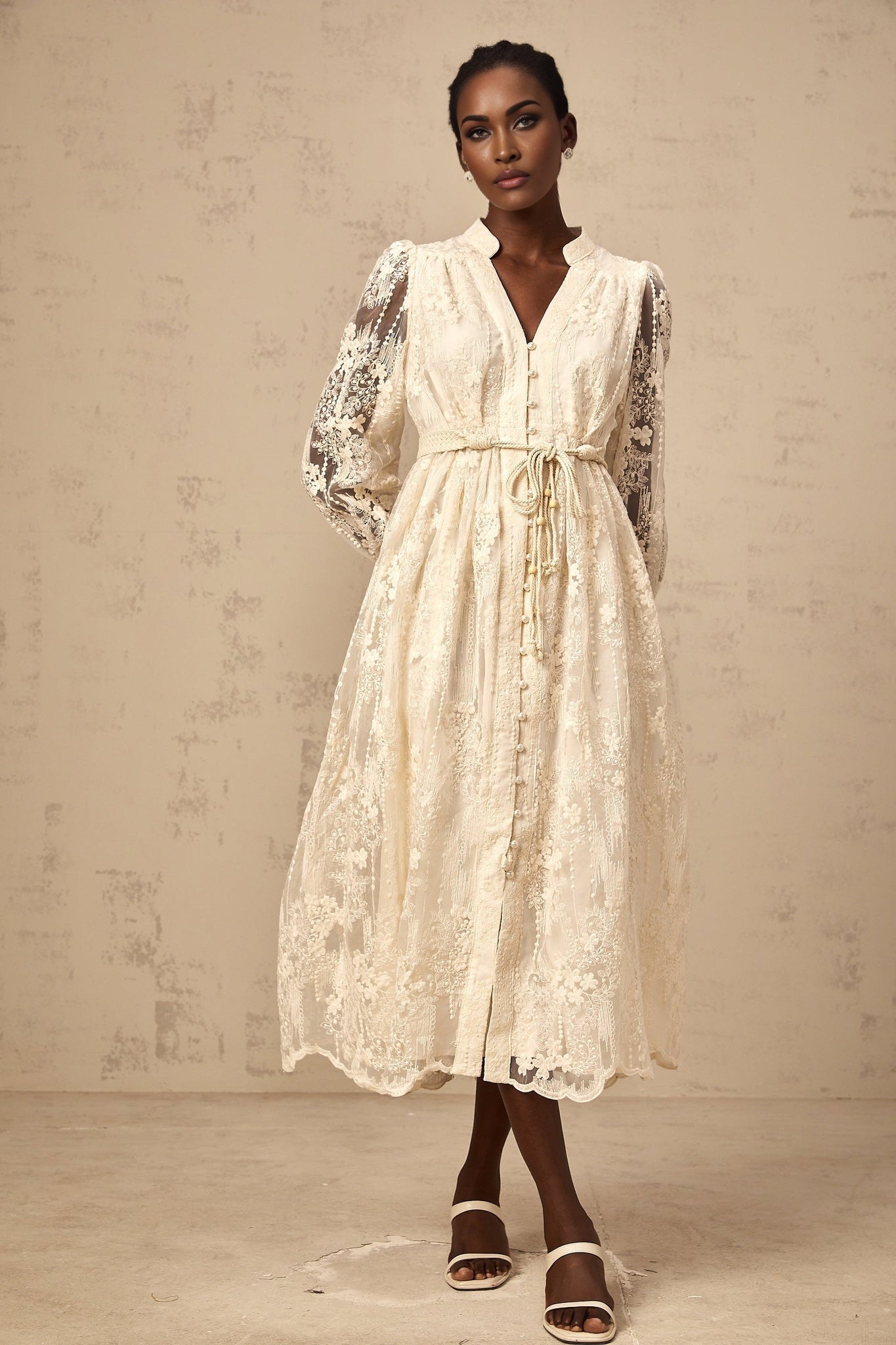 Woman wearing a neutral colored midi dress with lace embroidery details standing in a relaxed pose