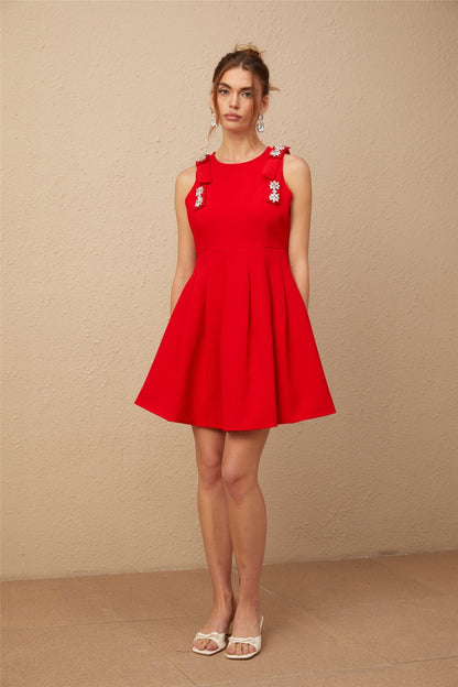 A sleeveless red mini dress with a pleated skirt and a bow detail named Louisa