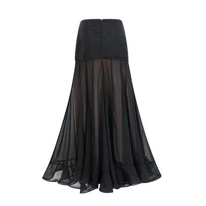 Young woman wearing a long flowy maxi skirt with ruffles and pleats in a soft fabric standing in a casual pose