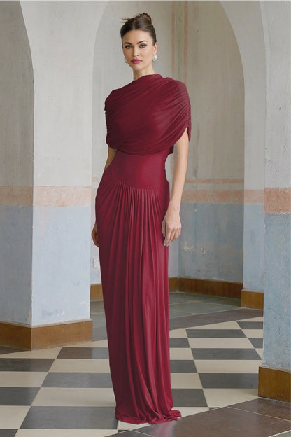 A red asymmetric maxi dress with pleated details and a long flowing skirt worn by a model