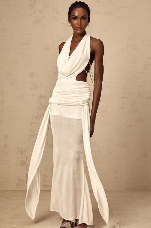 Woman wearing long white halterneck maxi dress with open back standing in sunlit outdoor setting