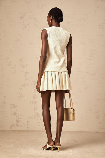 Woman wearing beige sequined knit vest top with matching skirt standing in casual pose