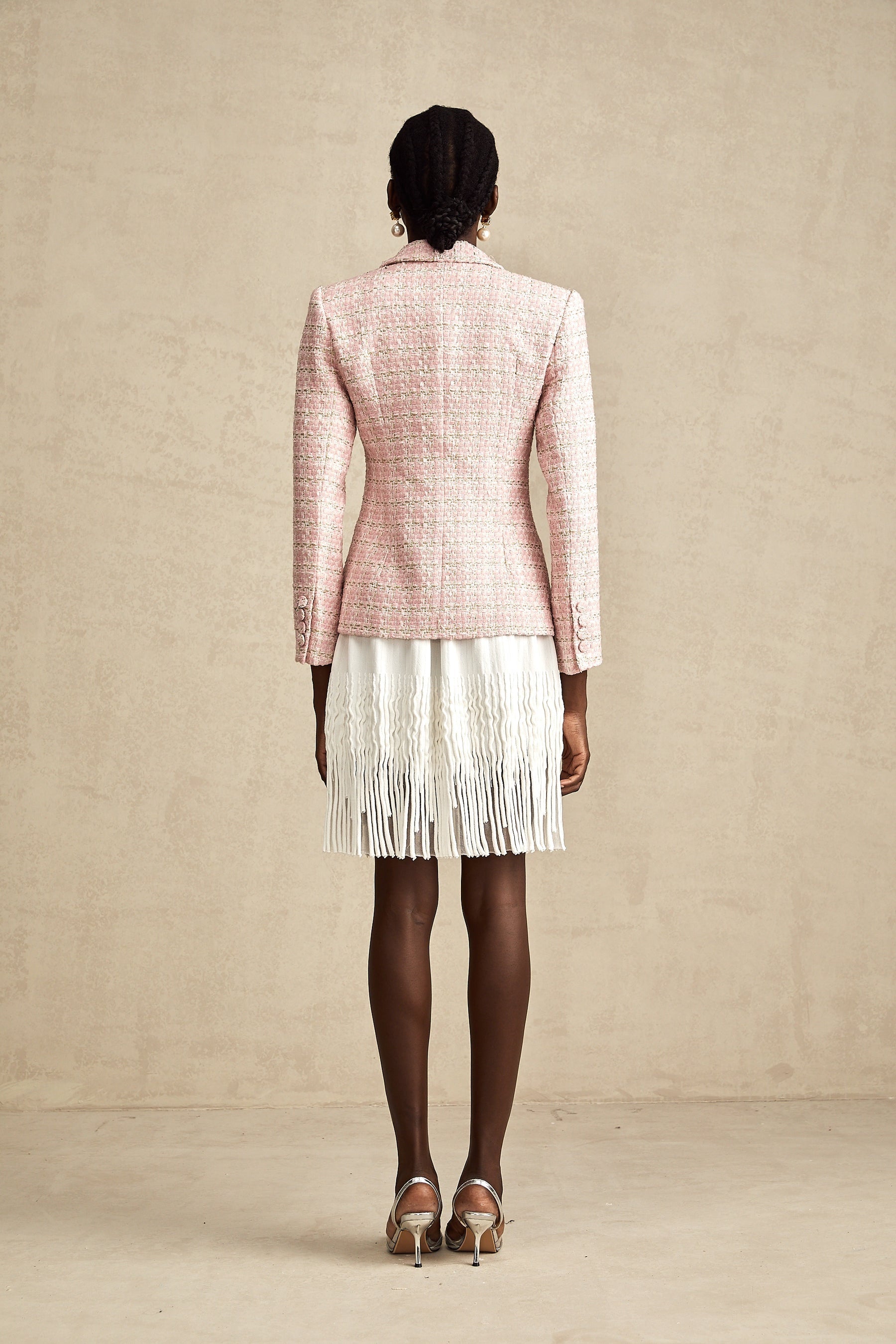 Woman wearing pink tweed blazer with crystal embellishments and check pattern