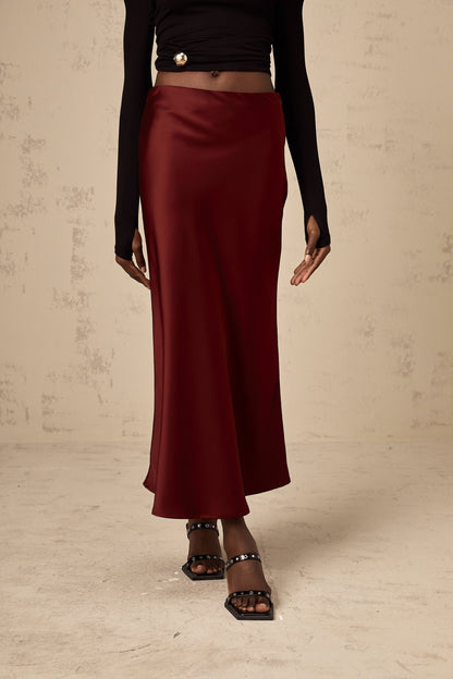 Bright red satin skirt with a flared silhouette hanging against a plain background