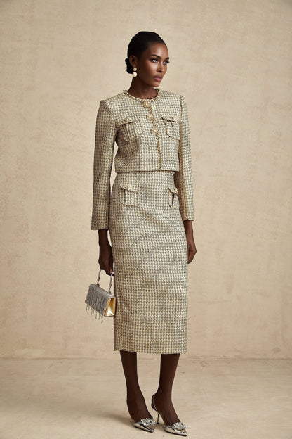 A woman wearing a gold tweed jacket and matching skirt set adorned with sequins The outfit sparkles in the light with a luxurious and festive appearance