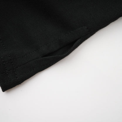 Woman wearing a black sleeveless top with ruched detailing and stretchy fabric