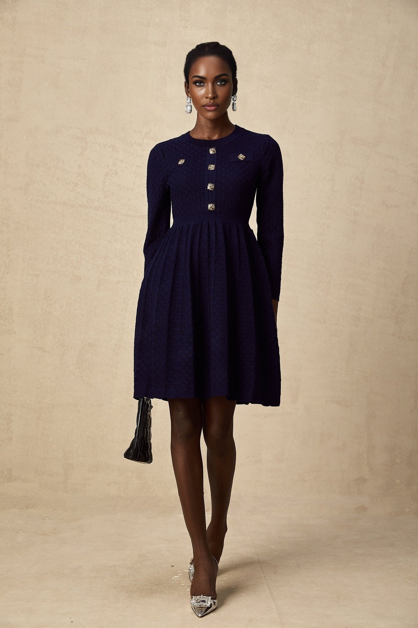 A navy blue mini dress with a basket weave texture worn by a model standing against a plain background