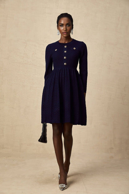 A navy blue mini dress with a basket weave texture worn by a model standing against a plain background
