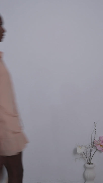 Young woman wearing a short sequin dress with floral pattern in vibrant colors standing against a plain background