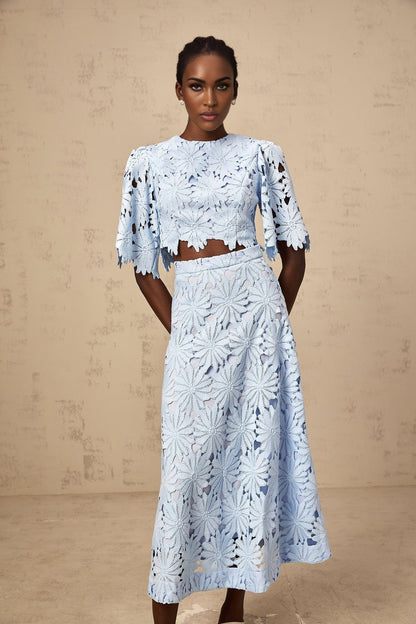 Woman wearing blue lace matching top and skirt set with floral pattern and scalloped edges