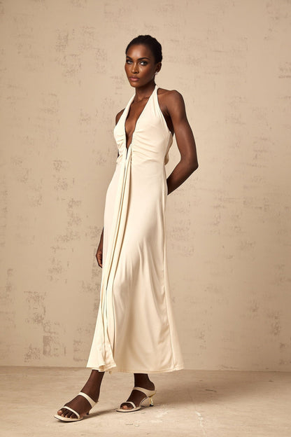 A woman wearing a long white maxi dress with a deep V neckline and draped fabric detail