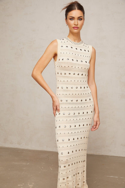 A long neutralcolored maxi dress with crochetknit pattern and studded details designed by Chloé