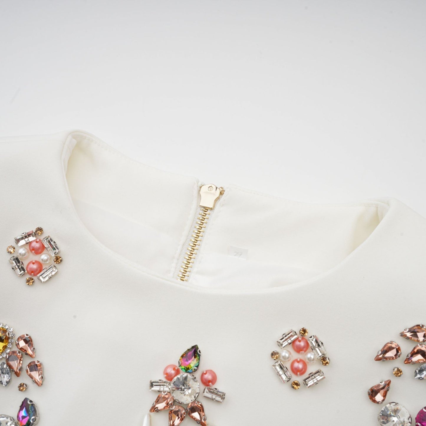 A white matching set consisting of a top and skirt adorned with crystal embellishments named Jeanne