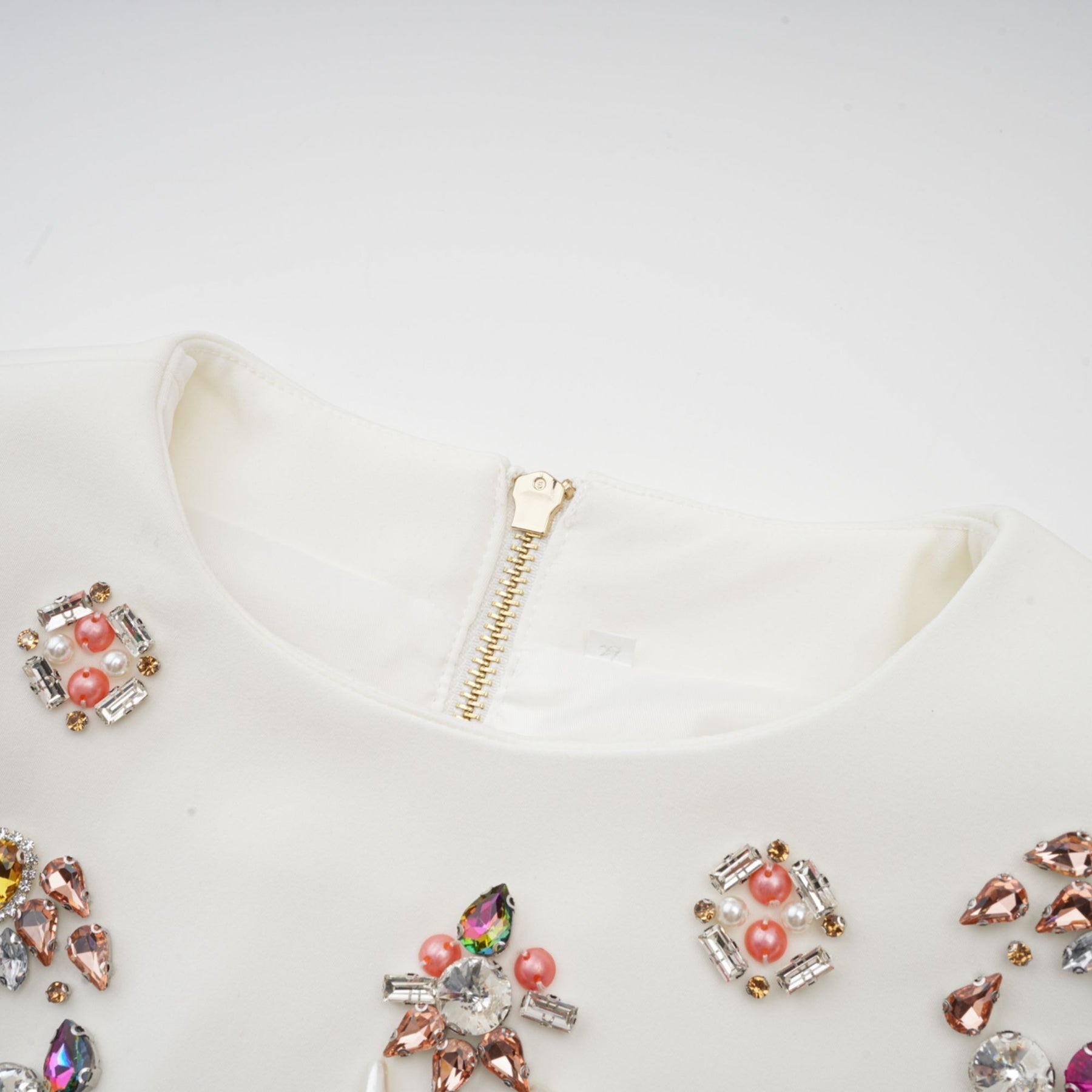 A white matching set consisting of a top and skirt adorned with crystal embellishments named Jeanne