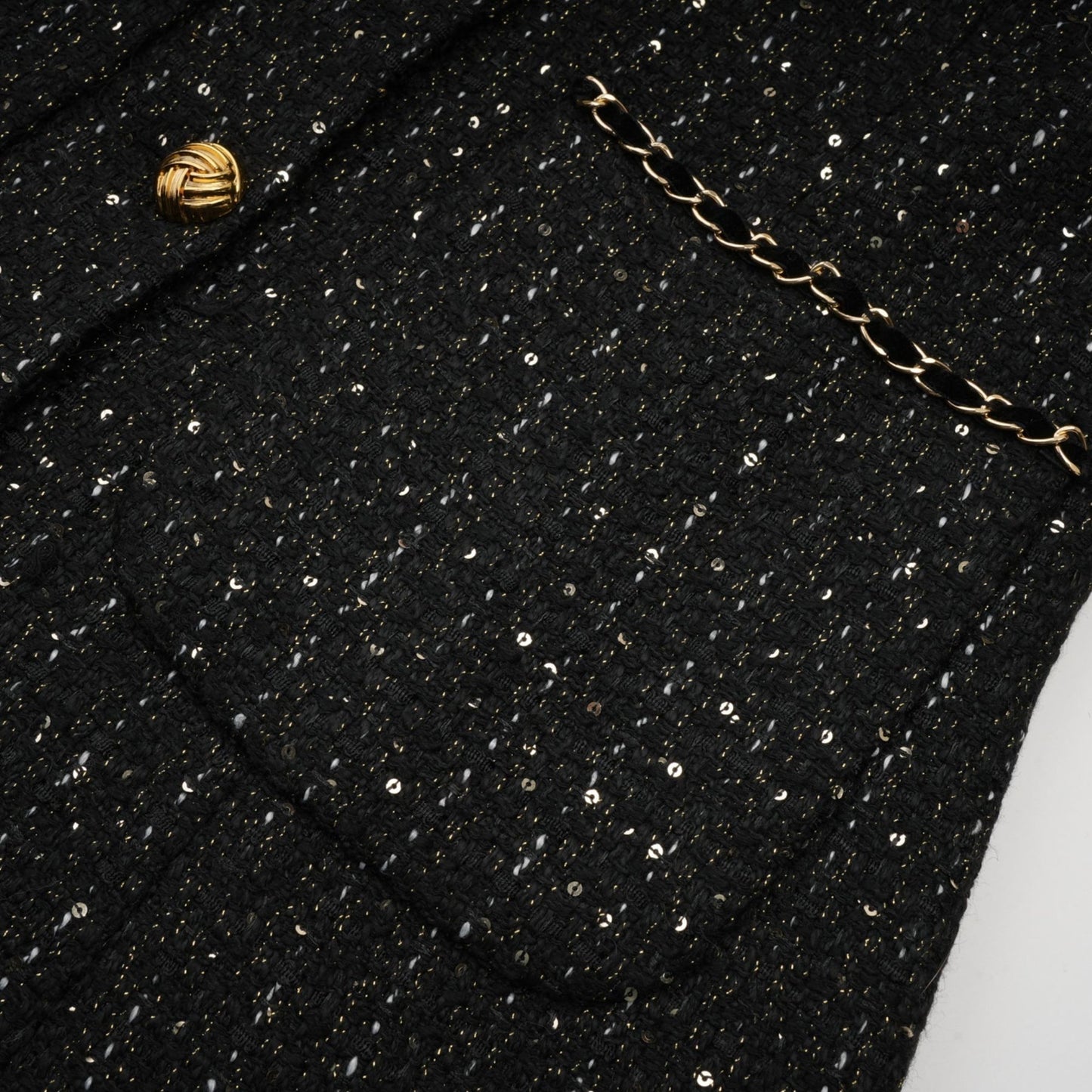 Woman wearing a black mini dress with sequin panels and tweed fabric short sleeves and form fitting silhouette
