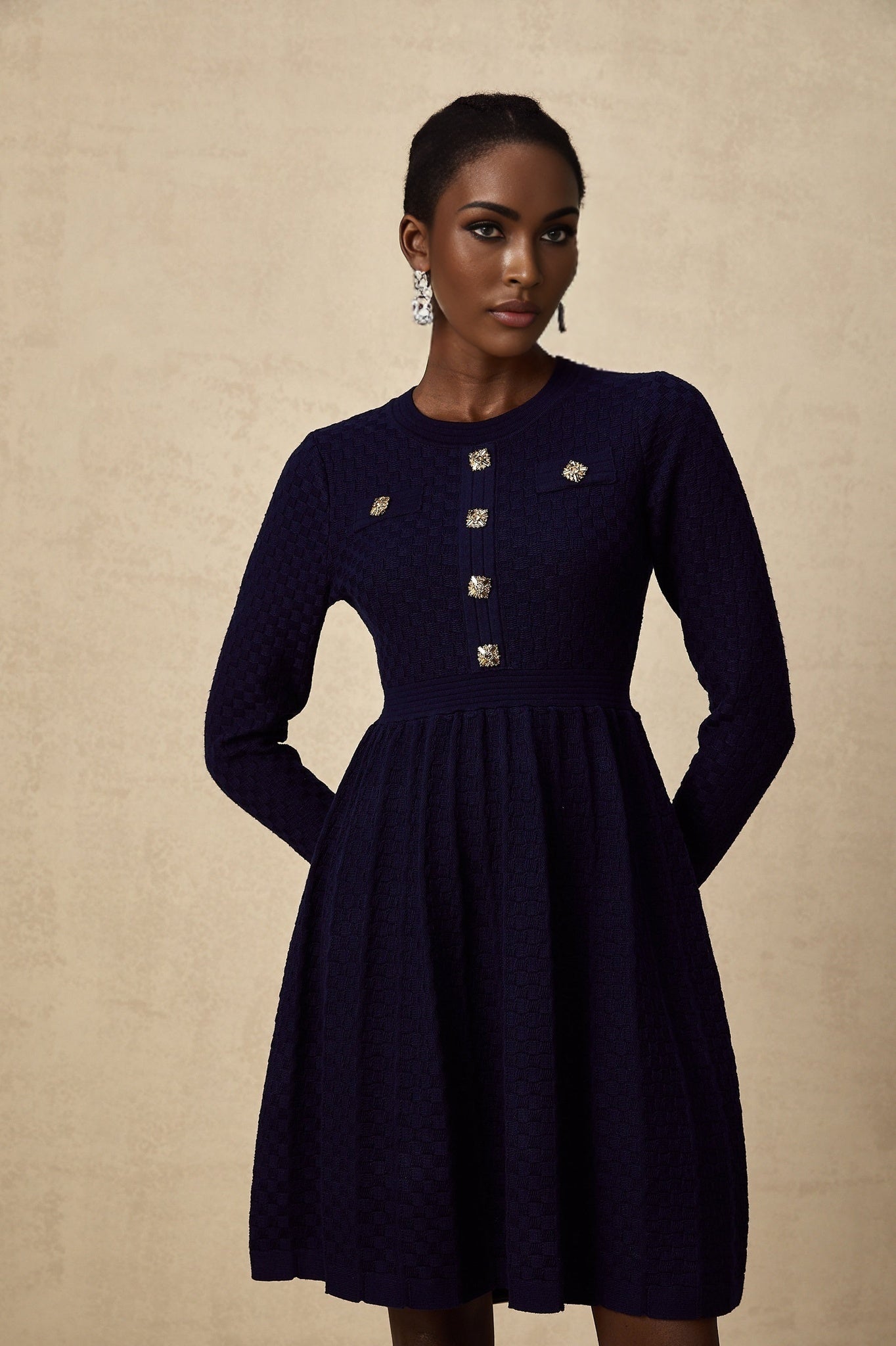 A navy blue mini dress with a basketweave texture worn by a model standing against a plain background