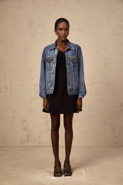 A light blue denim jacket adorned with sparkling rhinestones featuring a classic collar and button front closure