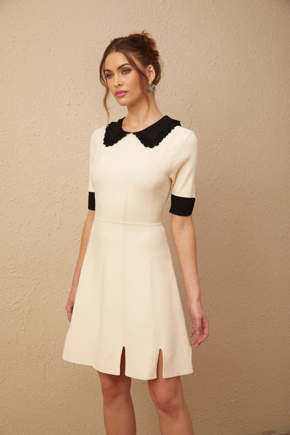 Young woman wearing a white knitted mini dress with split hem detail standing in a casual pose