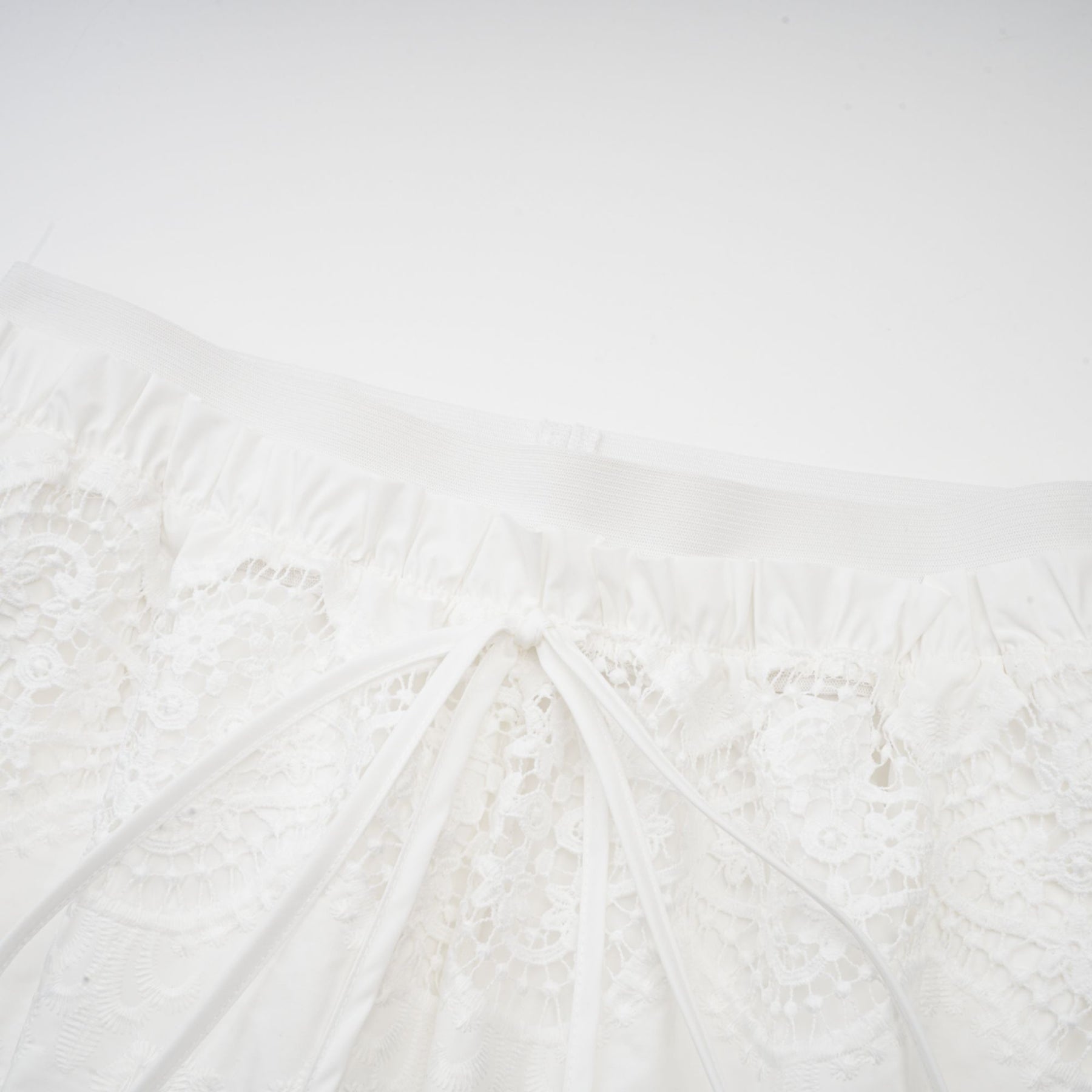 Woman wearing white lace trim cropped top and matching trousers set with cutout details