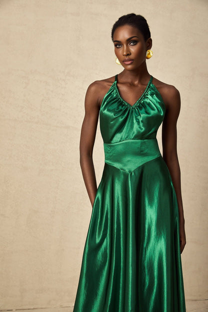 A woman wearing an emerald green satin midi dress with an open back design