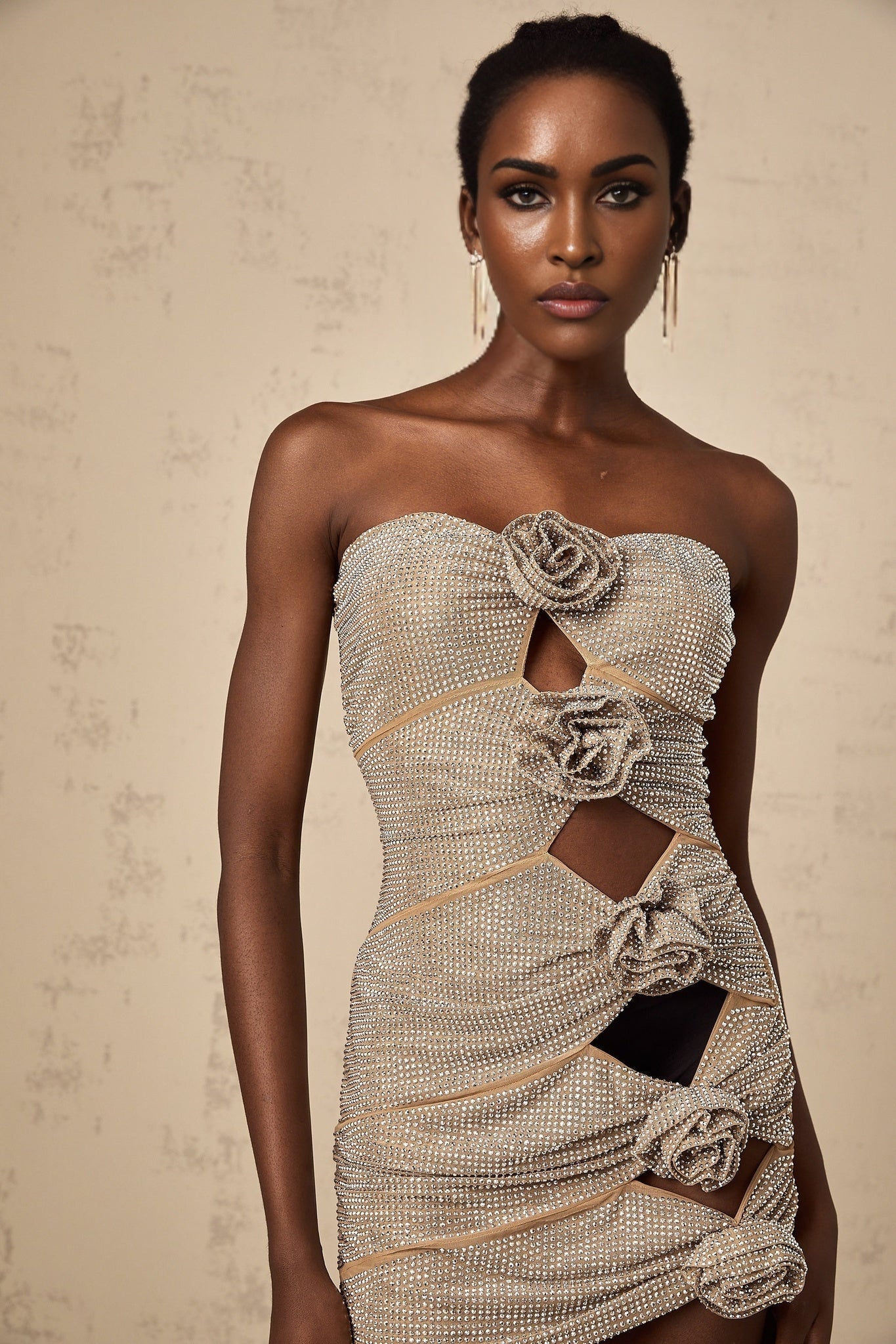 A short black mini dress with rhinestone embellishments and strategically placed cutouts featuring a fitted silhouette and sleeveless design