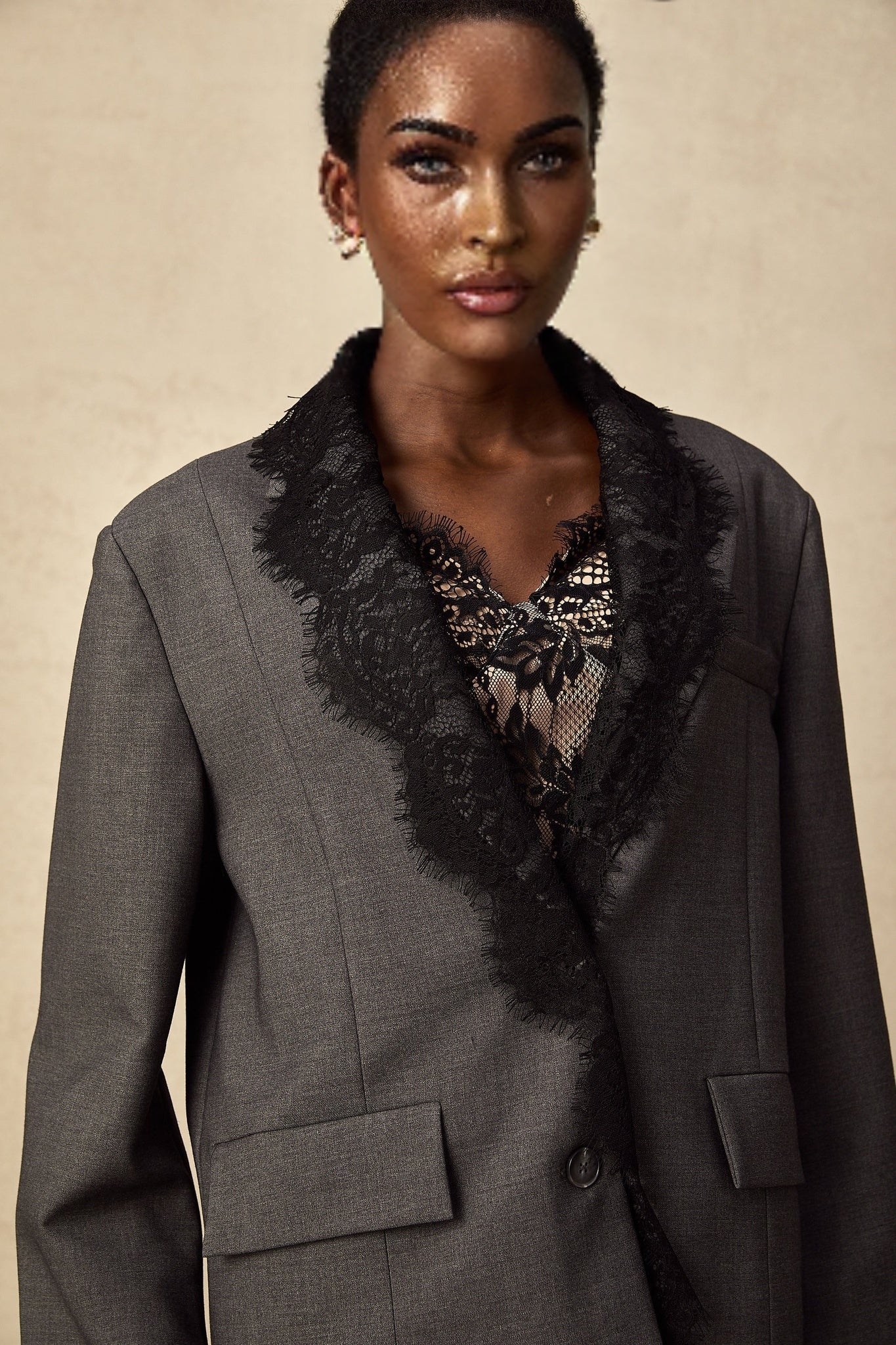 Woman wearing grey blazer with lace panel details on sleeves and lapels