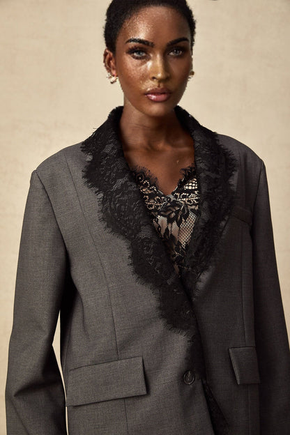 Woman wearing grey blazer with lace panel details on sleeves and lapels
