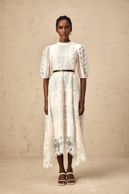 Woman wearing a white midi dress with lace trim panels and a belt at the waist