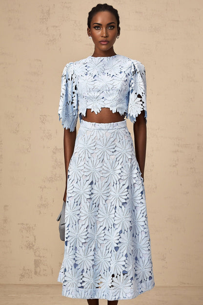 Woman wearing blue lace top and matching skirt set named Audrey with intricate guipure lace pattern