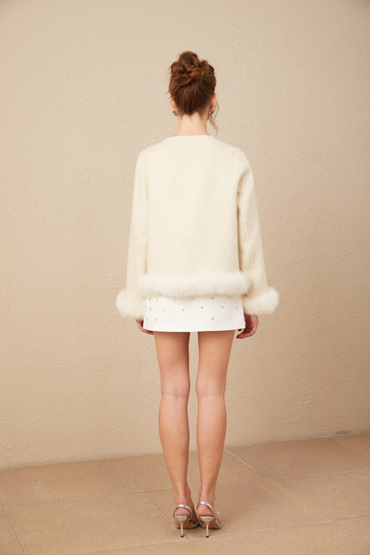 A woman wearing a two tone short coat with a large bowknot detail at the waist The coat features contrasting colors and a fitted silhouette
