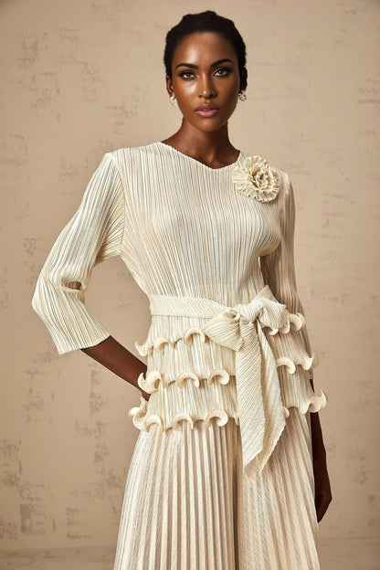 A woman wearing a floral jumpsuit with ruffles and pleats featuring applique flowers