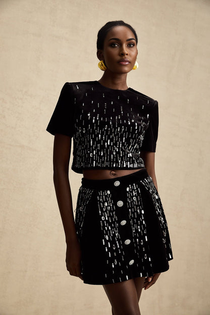 Woman wearing black velvet matching set with embellished top and skirt named Isabeau