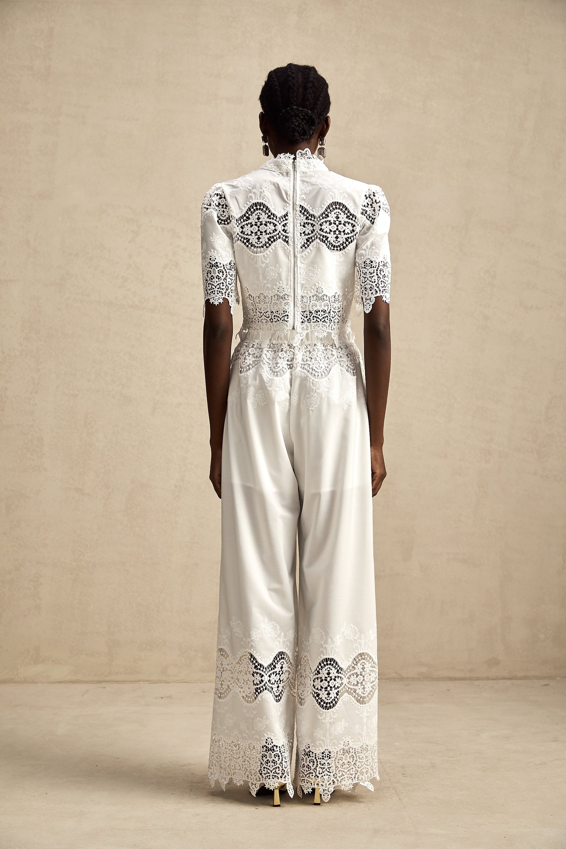 Woman wearing white lace trim cropped top and matching trousers with cutout details Raphaelle matching set