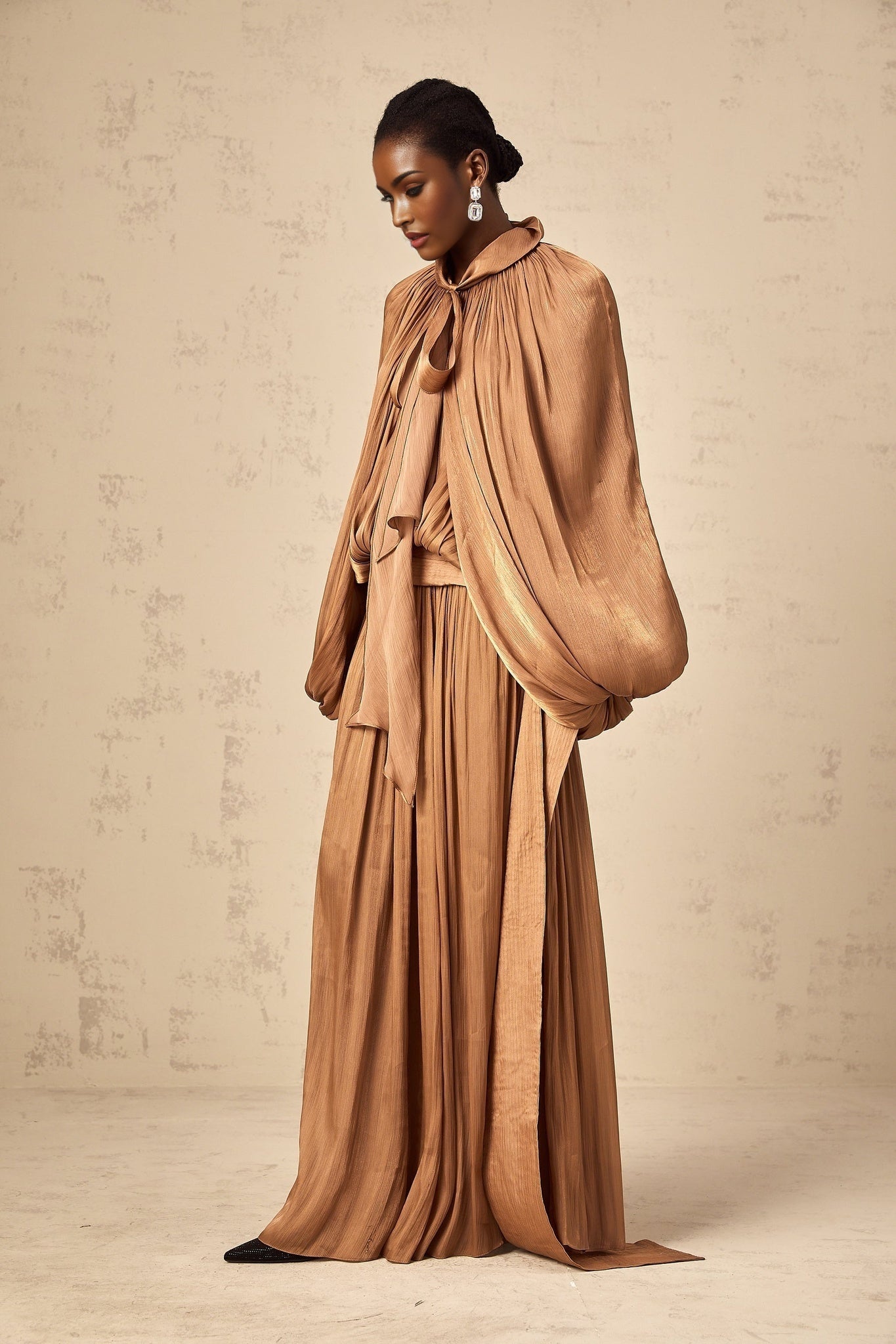 A long brown satin maxi dress with pleated details and a flowing silhouette