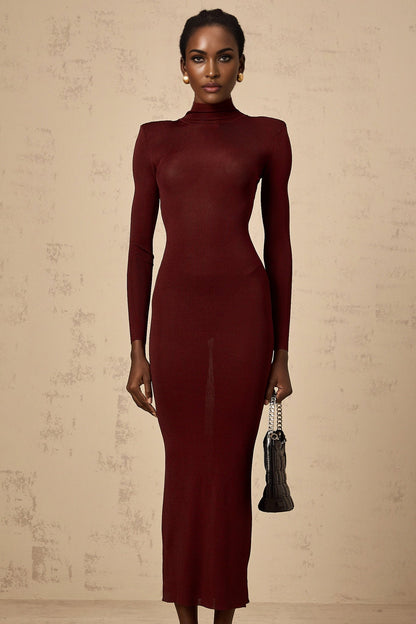 A red knitted midi dress with a semi sheer texture worn by a model standing against a plain background
