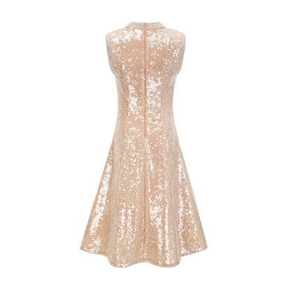 A woman wearing a sparkling midi length dress with sequins and faux pearls adorning the fabric standing in an elegant pose