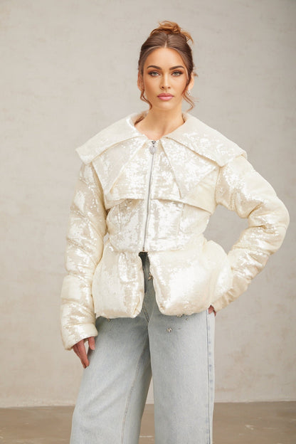 Woman wearing long white sequined down coat with hood and zipper closure
