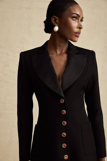 Woman wearing long black blazer dress with single button closure and lapel collar