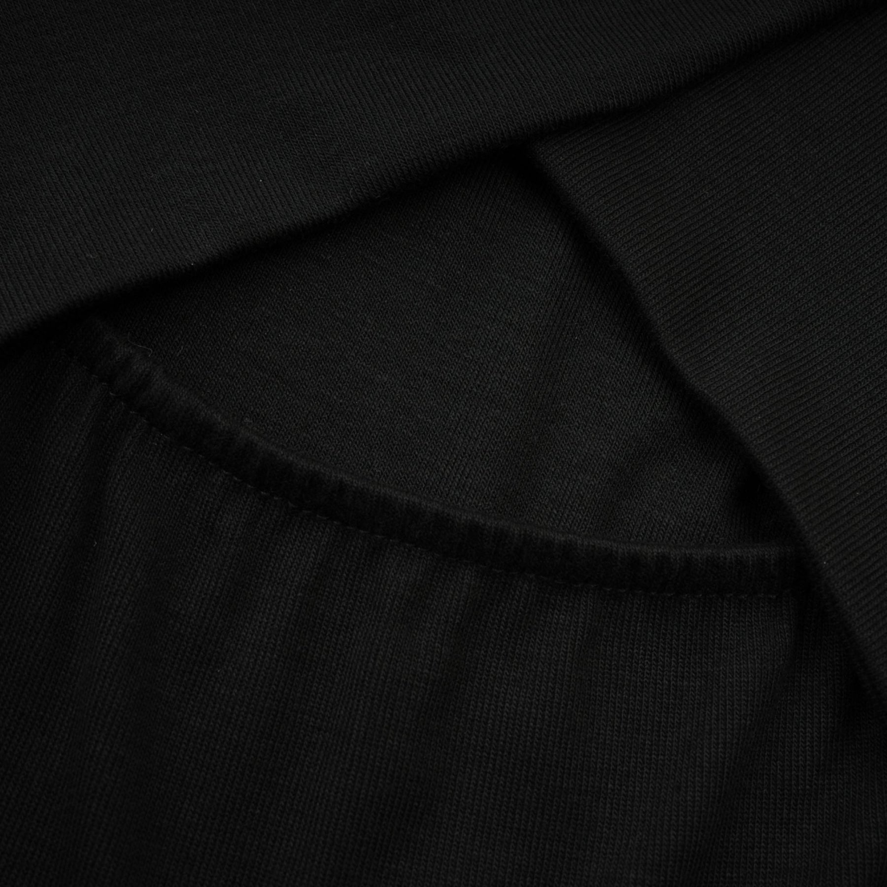 A black ruched top with long sleeves made of stretchy jersey fabric called Odette