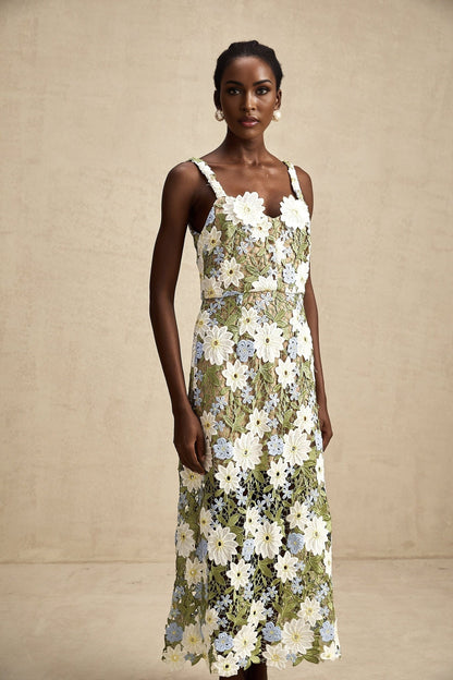 A woman wearing a floral embroidered midi dress with hollow carved details standing in a relaxed pose against a plain background