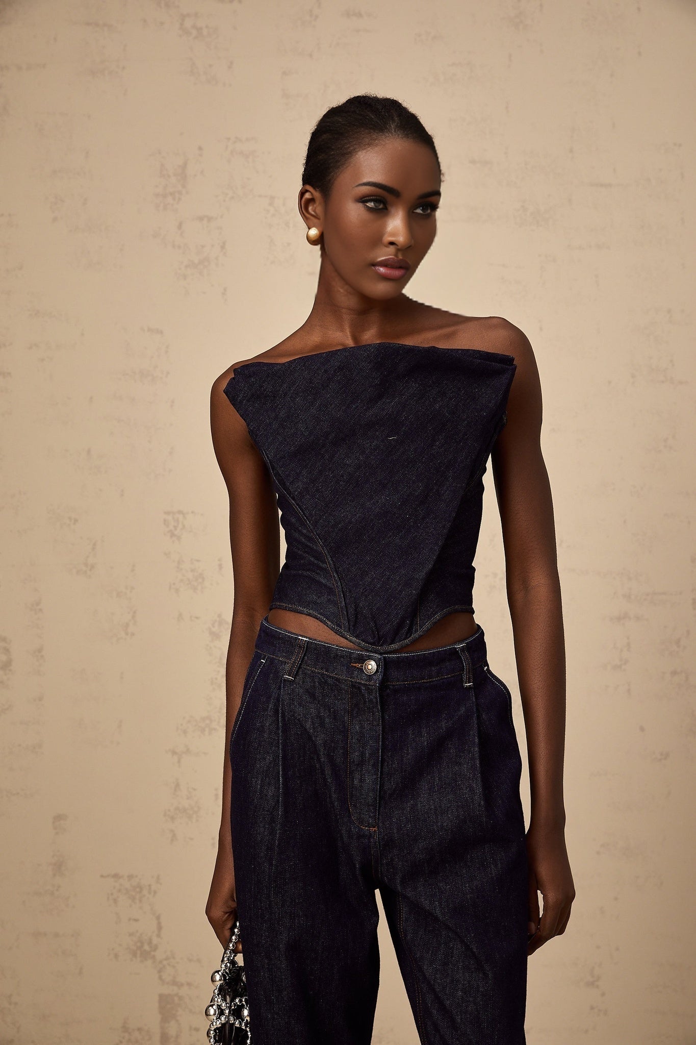 A dark blue offshoulder denim top by Kleber worn by a model against a plain background
