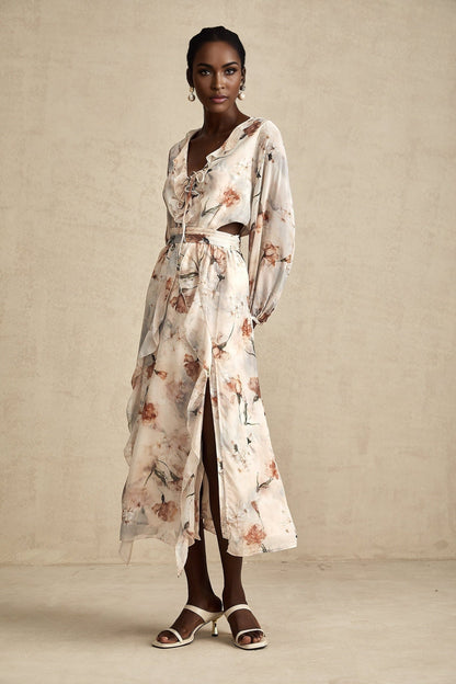A woman wearing a floral print midi dress with an open waist design The dress features a Berengere style with a colorful floral pattern on a light background