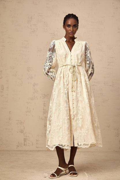 A woman wearing a neutralcolored midi dress with delicate lace embroidery details standing in a casual pose