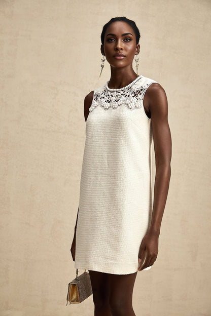 A woman wearing a short tweed dress with embroidery details and cutout sections