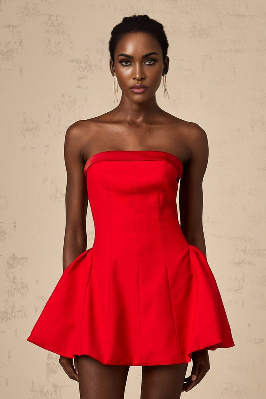 A woman wearing a vibrant red offshoulder mini dress with a flared skirt standing against a plain background