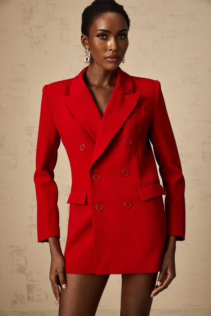 Woman wearing a red doublebreasted blazer with lapels and buttons against a plain background