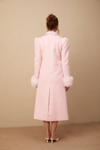 A pink overcoat made of faux fur named Louisette hanging on a clothing rack