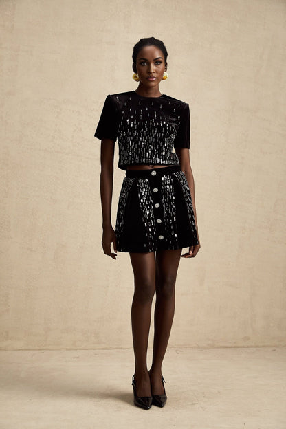 A black velvet two piece outfit consisting of a top and skirt set embellished with decorative details named Isabeau