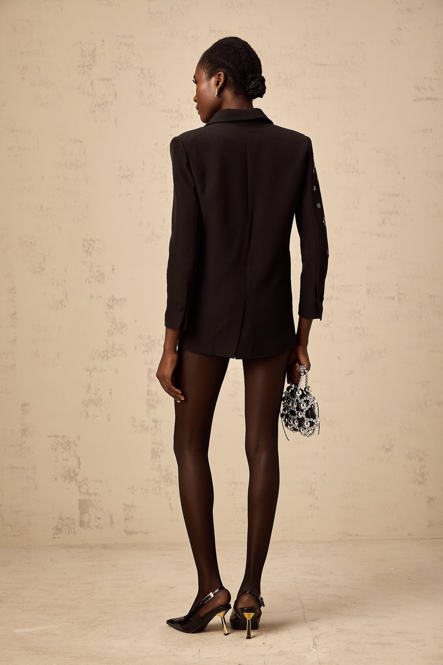 A black blazer with star appliques worn by a woman against a plain background